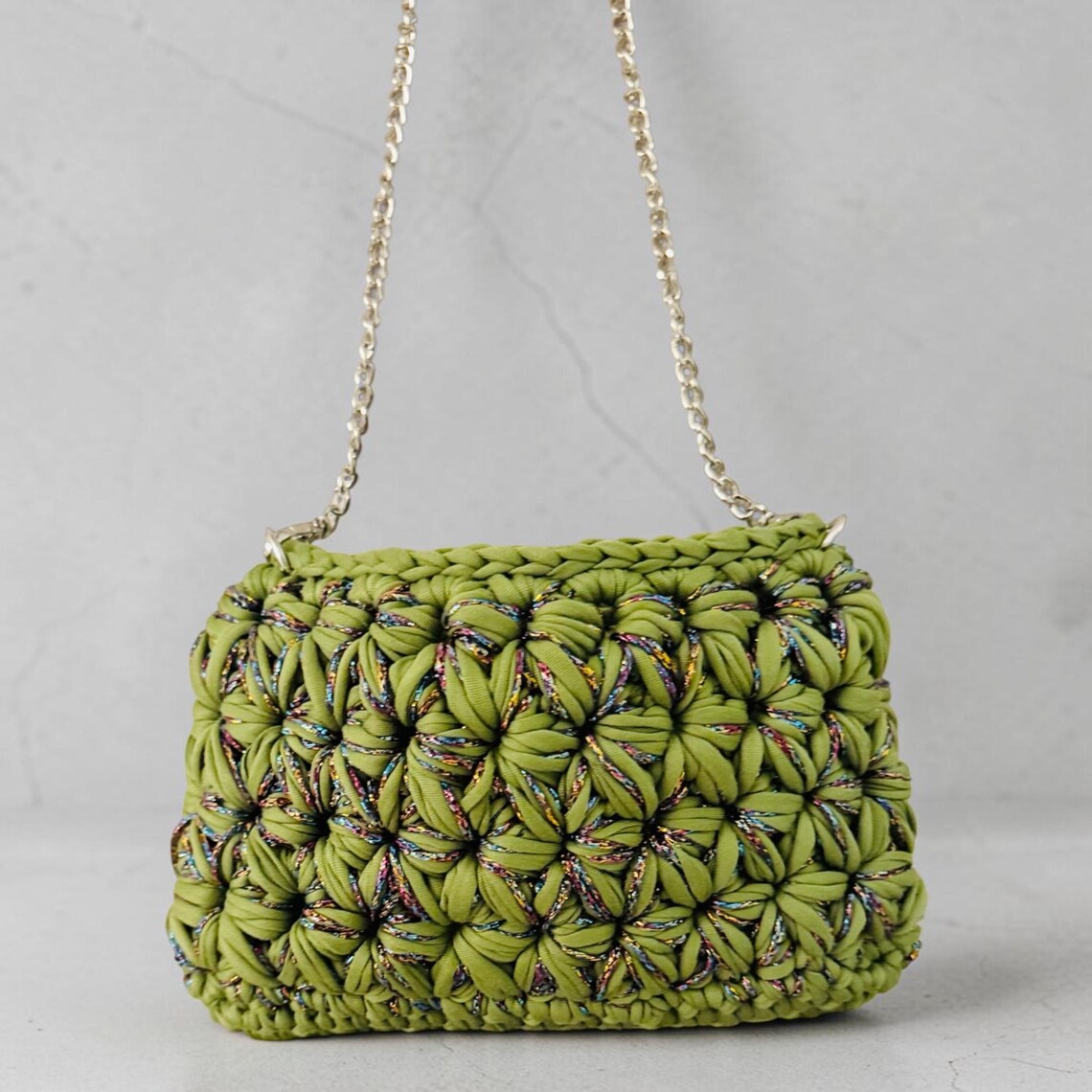 Handmade avocado green crochet shoulder bag with textured floral design and gold chain strap
