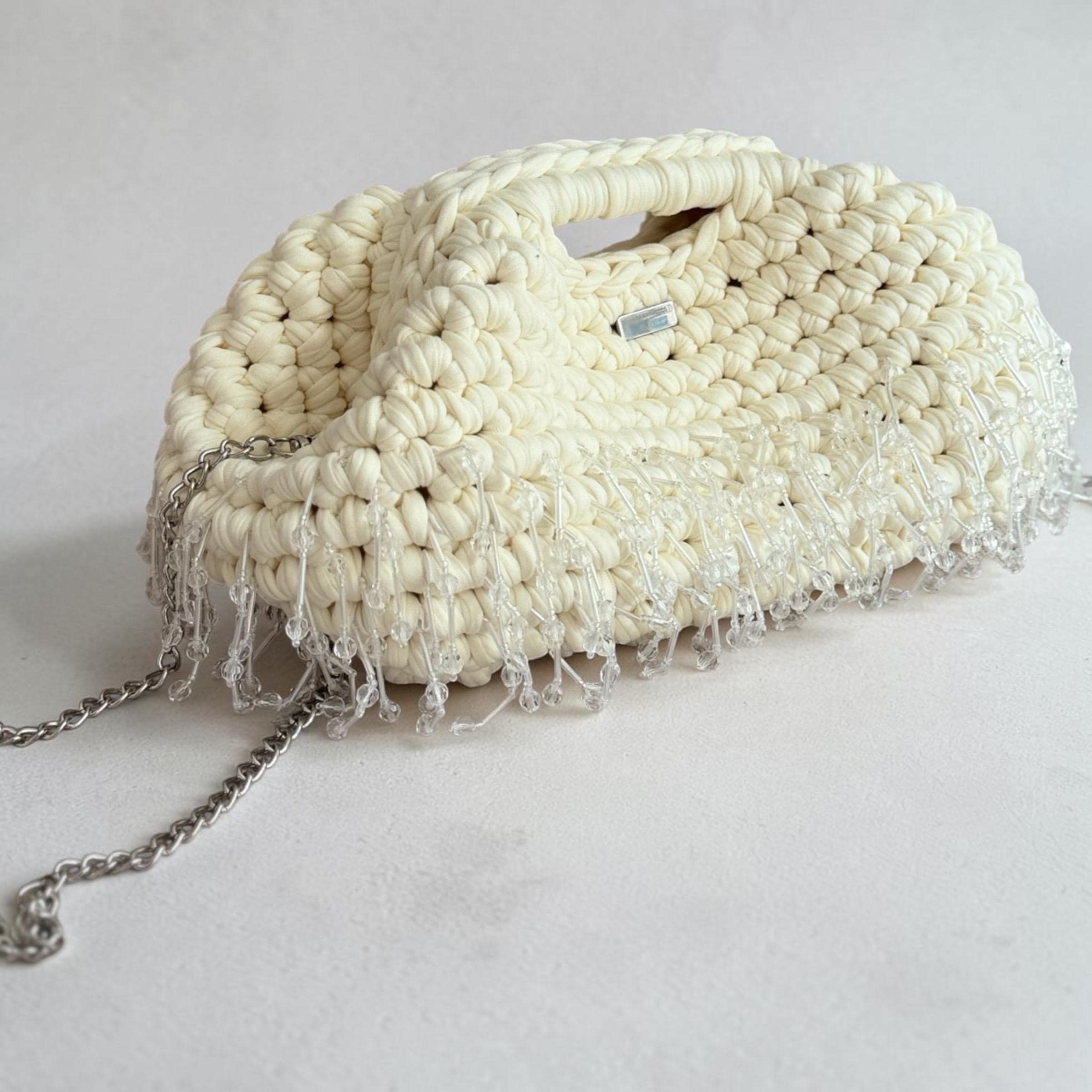 Cream crochet clutch with white beaded tassel details and fermoir clasp