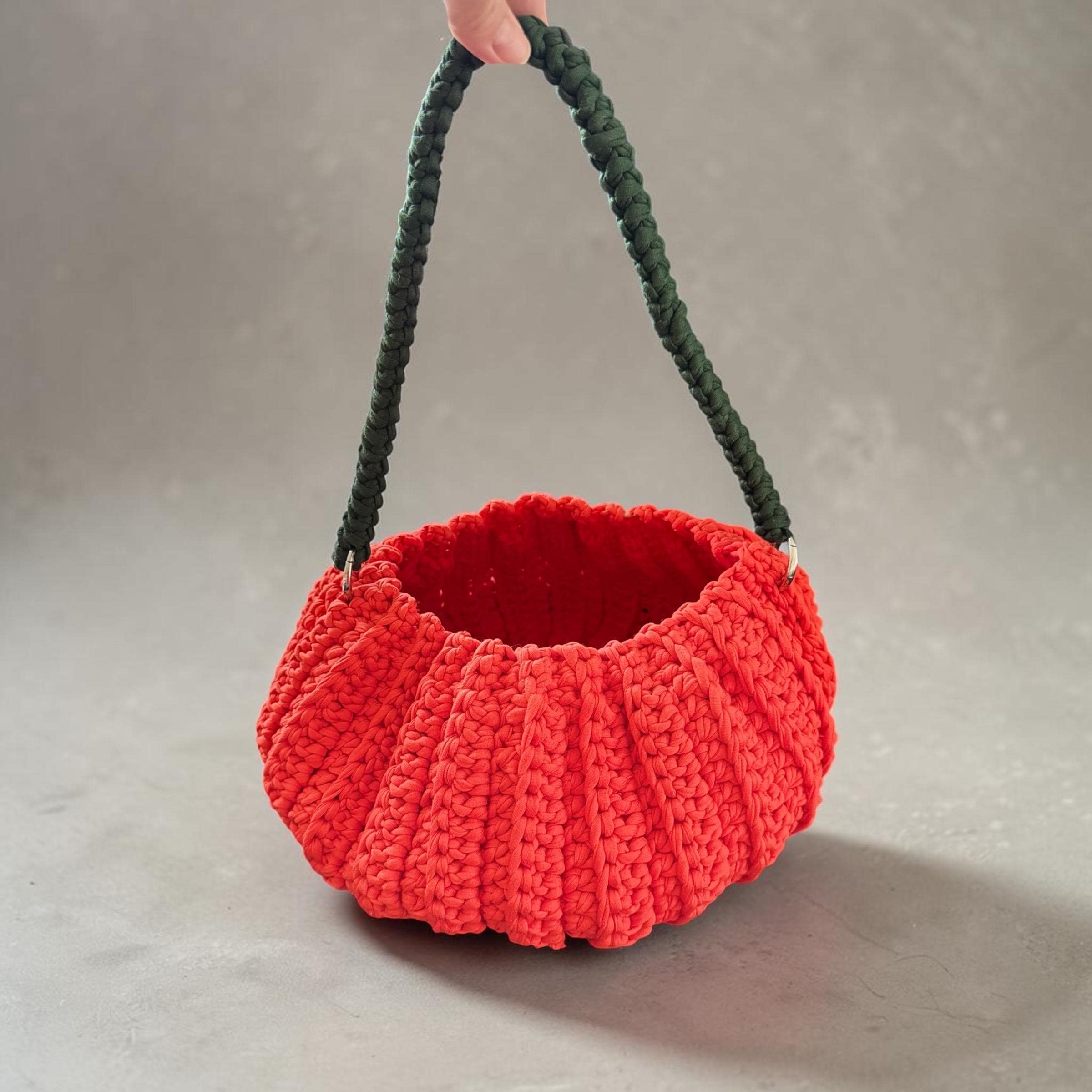 Orange crochet pumpkin bag with a green braided handle
